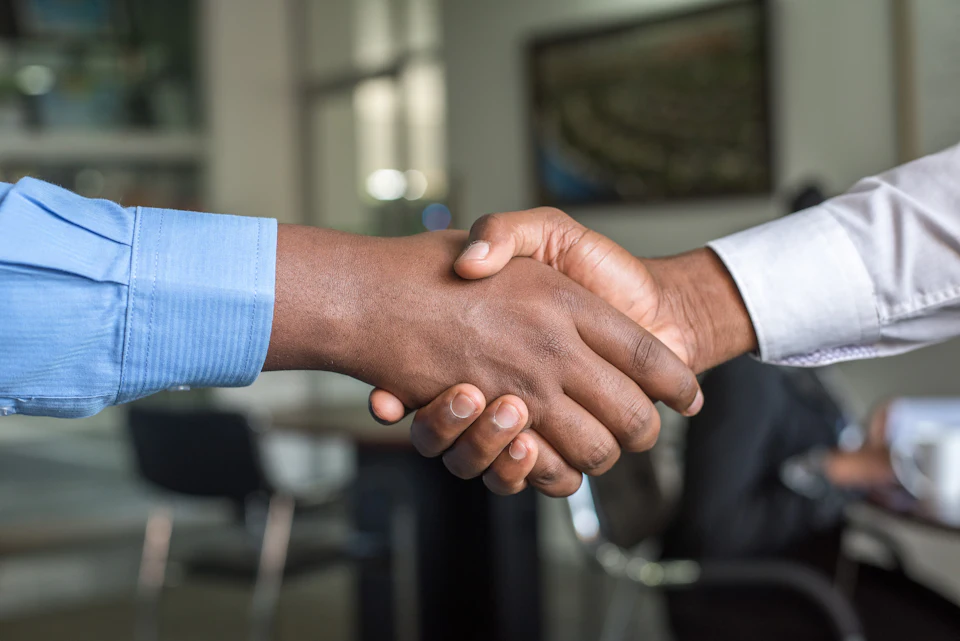 Two professionals shaking hands across a desk